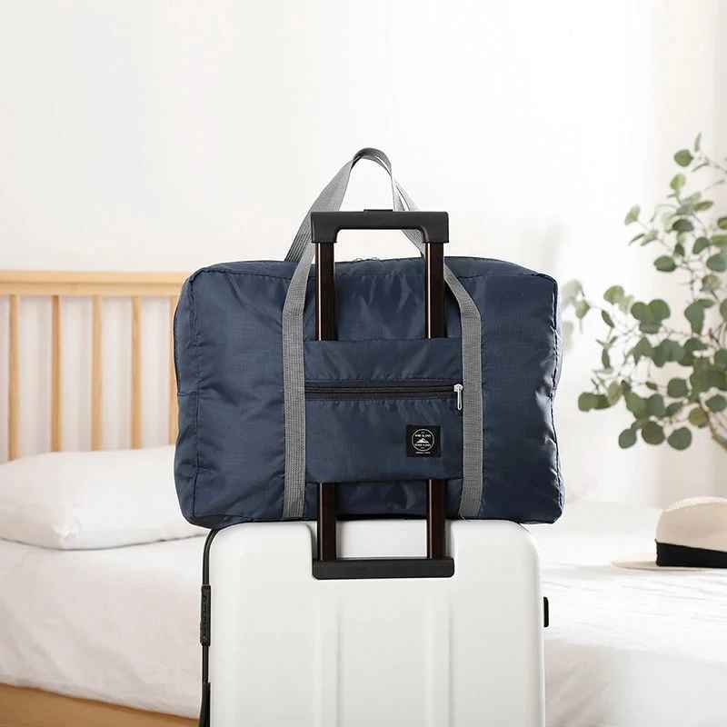 Navy Blue foldable travel duffel bag with carry handles and front zip pocket.